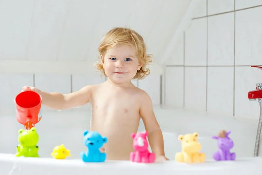 Bambin jouant dans le bain avec un gobelet rouge et des jouets colorés
