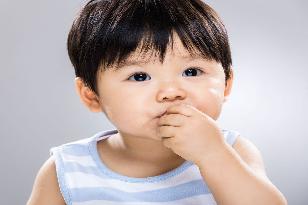 Bébé qui porte les doigts à sa bouche pour faire le signe « manger »