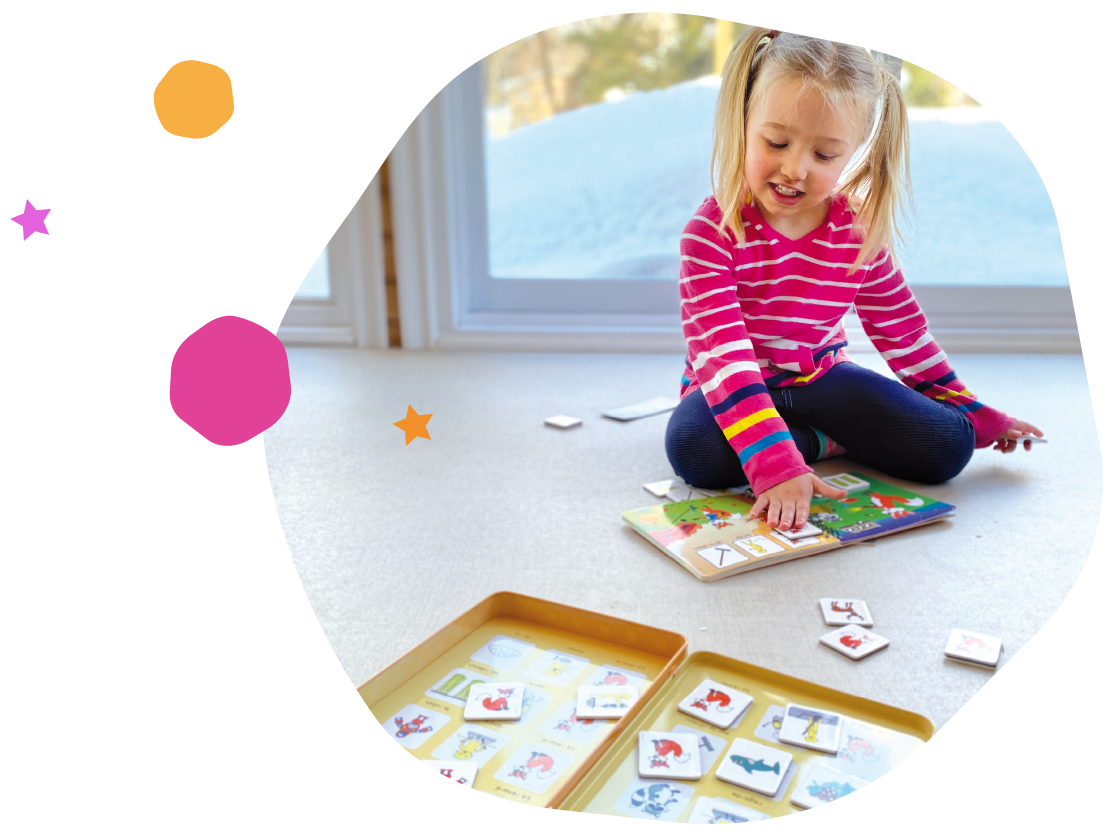 Girl sitting on the floor playing with a magnetic book and trays of magnetic pictograms