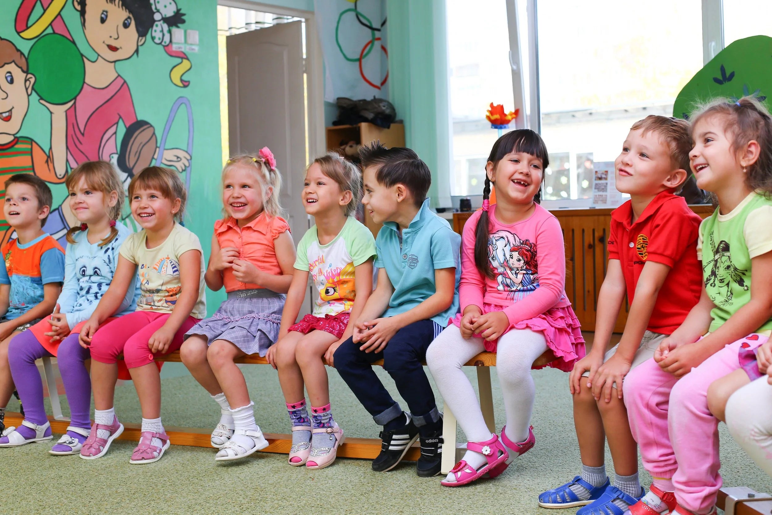 Groupe d'enfants assis sur un banc, riant ensemble à la garderie